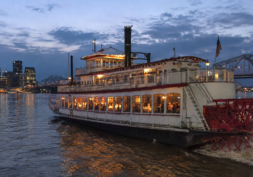 A large white paddle steamer riverboat cruise on the Ohio River in Louisville Kentucky.